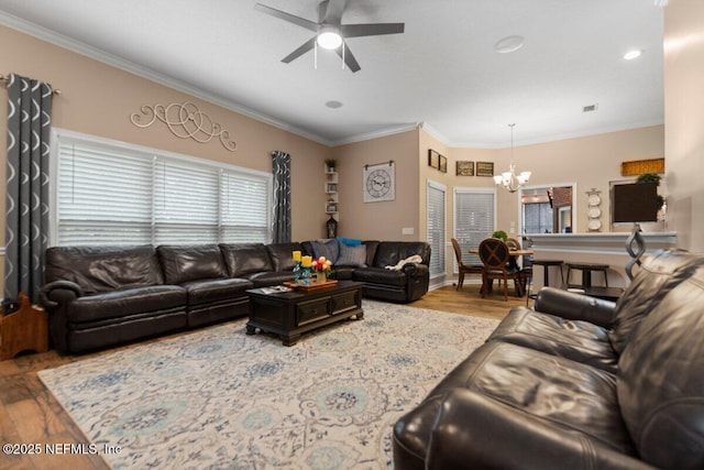 living area with visible vents, ornamental molding, wood finished floors, and ceiling fan with notable chandelier