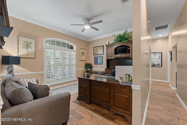 office with ornamental molding, light wood-type flooring, visible vents, and a ceiling fan