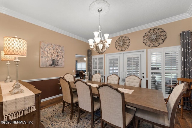 dining room with french doors, crown molding, an inviting chandelier, and wood finished floors