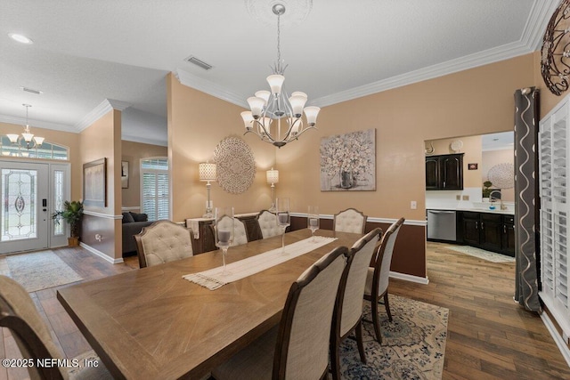 dining space featuring crown molding, wood finished floors, visible vents, and an inviting chandelier