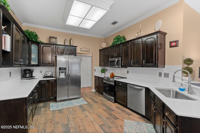 kitchen with light wood-style flooring, dark brown cabinetry, a sink, visible vents, and appliances with stainless steel finishes