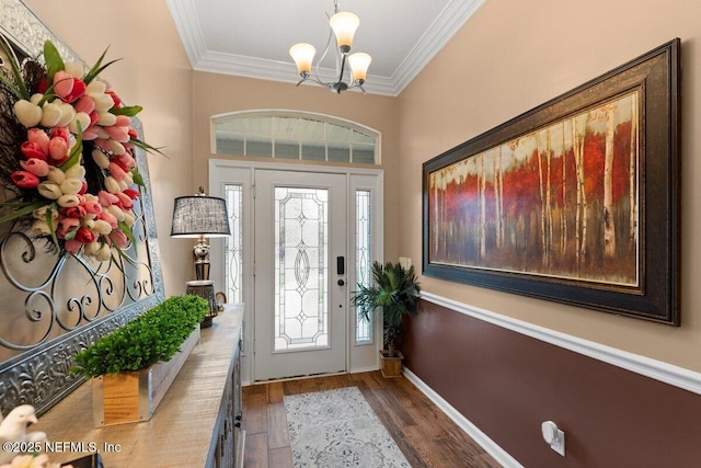 entrance foyer with dark wood-type flooring, a chandelier, crown molding, and baseboards