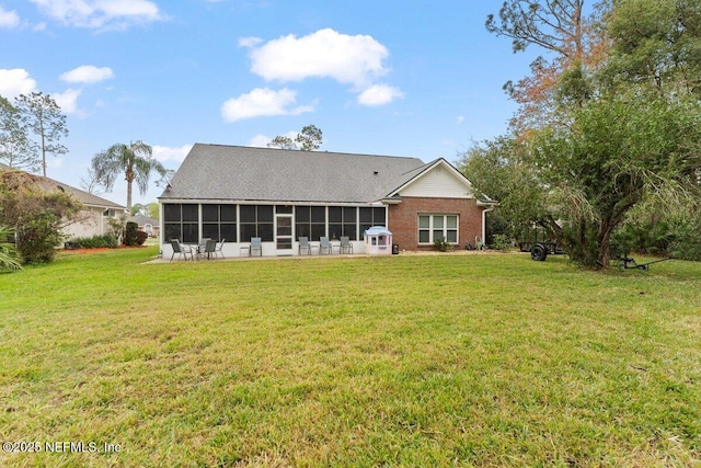 rear view of property with a sunroom, a lawn, and brick siding