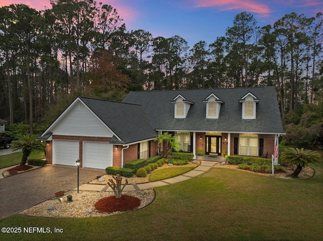 cape cod home with brick siding, decorative driveway, and an attached garage