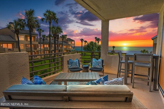 patio terrace at dusk featuring an outdoor hangout area, a balcony, and a water view