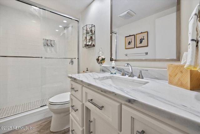 bathroom with visible vents, a stall shower, toilet, and wood finished floors