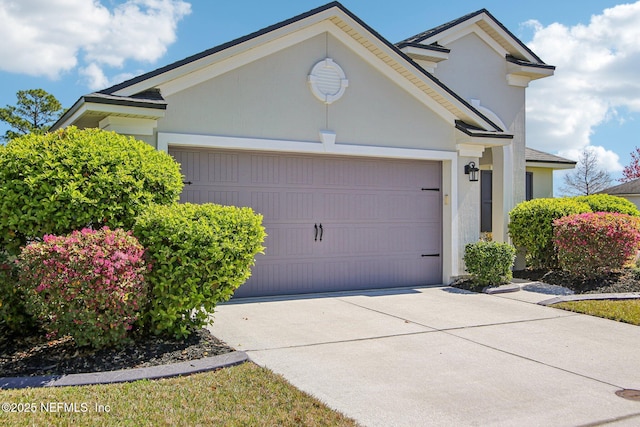 view of front of property with concrete driveway, an attached garage, and stucco siding