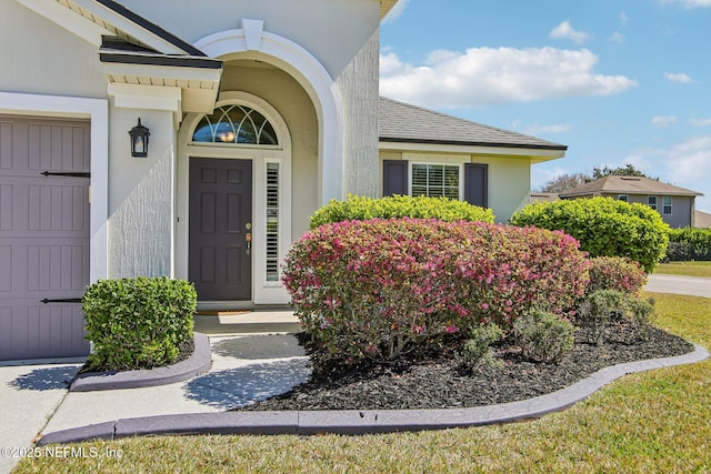 entrance to property with roof with shingles and stucco siding