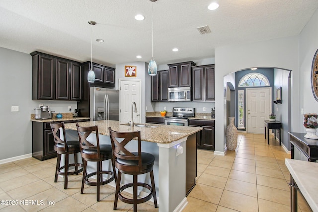 kitchen with arched walkways, light tile patterned floors, stainless steel appliances, a sink, and visible vents