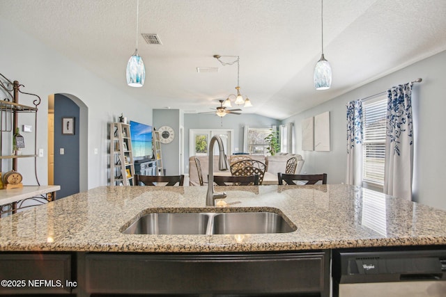 kitchen featuring arched walkways, dishwasher, open floor plan, pendant lighting, and a sink