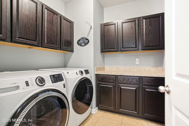 clothes washing area with light tile patterned floors, cabinet space, and washer and dryer