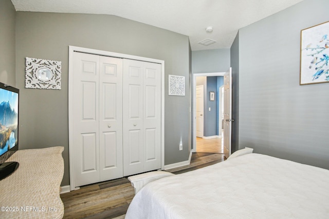 bedroom featuring a closet, baseboards, vaulted ceiling, and wood finished floors