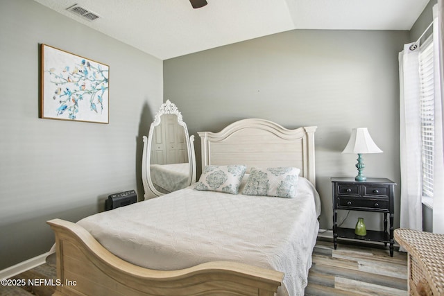 bedroom with lofted ceiling, wood finished floors, visible vents, and a ceiling fan