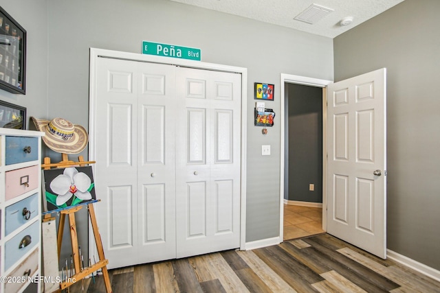 bedroom with visible vents, baseboards, a closet, and wood finished floors