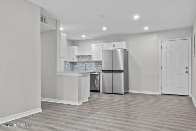 kitchen with light wood finished floors, visible vents, white cabinets, stainless steel appliances, and light countertops