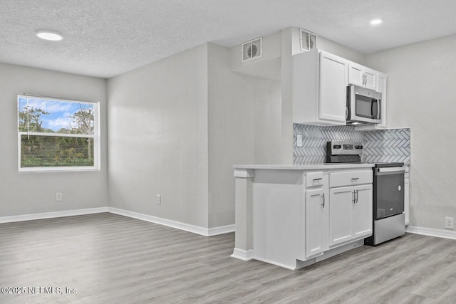 kitchen featuring white cabinets, light wood finished floors, appliances with stainless steel finishes, and light countertops