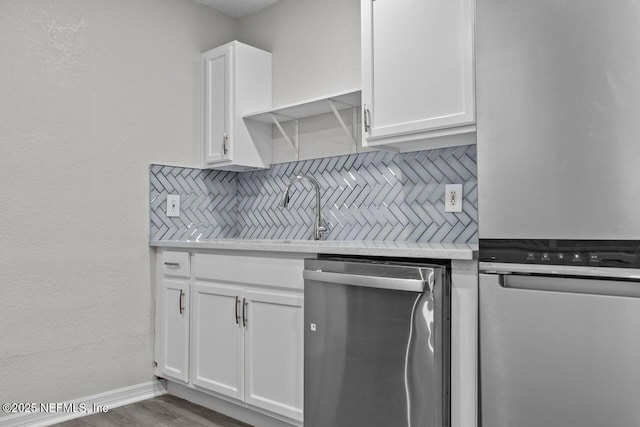 kitchen featuring stainless steel appliances, white cabinets, light countertops, and tasteful backsplash