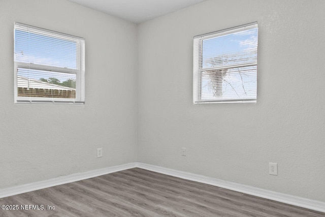 spare room with baseboards and dark wood finished floors