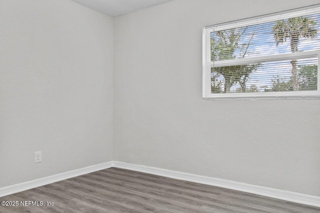 unfurnished room with dark wood-style floors and baseboards