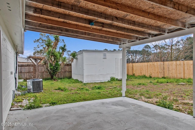 view of patio featuring central air condition unit, a storage shed, a fenced backyard, and an outbuilding