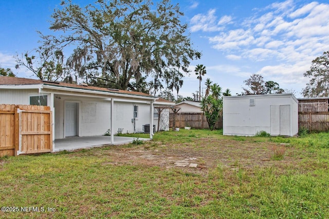 view of yard with a patio area, a fenced backyard, central AC, and a storage unit