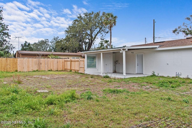 rear view of property with a yard, fence, and a patio