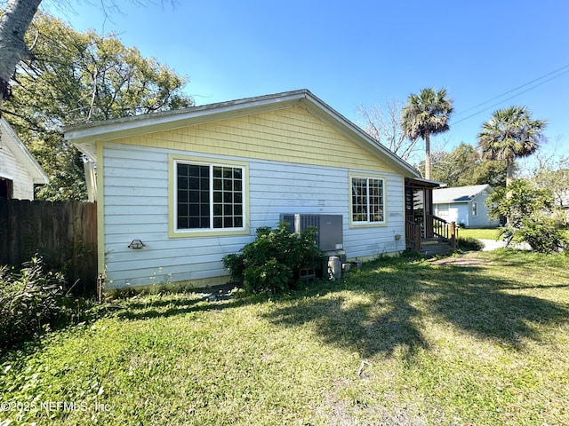 back of property with fence, a lawn, and central AC