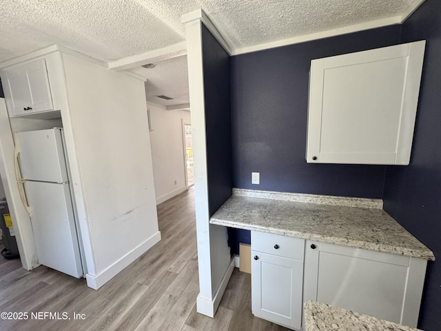 kitchen with freestanding refrigerator, white cabinetry, a textured ceiling, and light wood finished floors