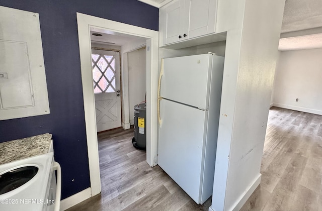 kitchen featuring light wood-type flooring, freestanding refrigerator, electric panel, and white cabinetry