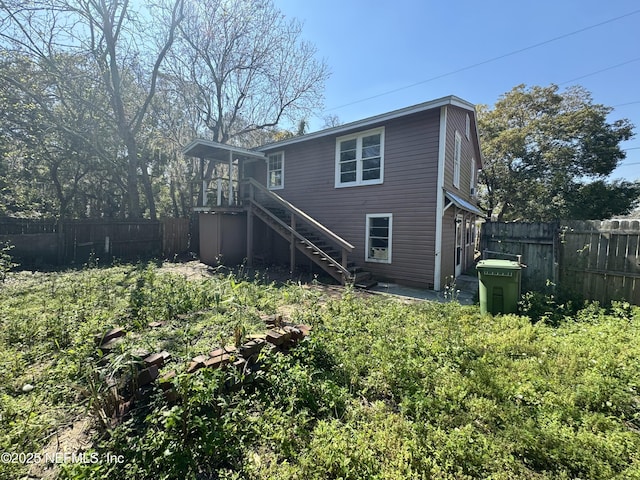 back of property featuring a fenced backyard and stairway