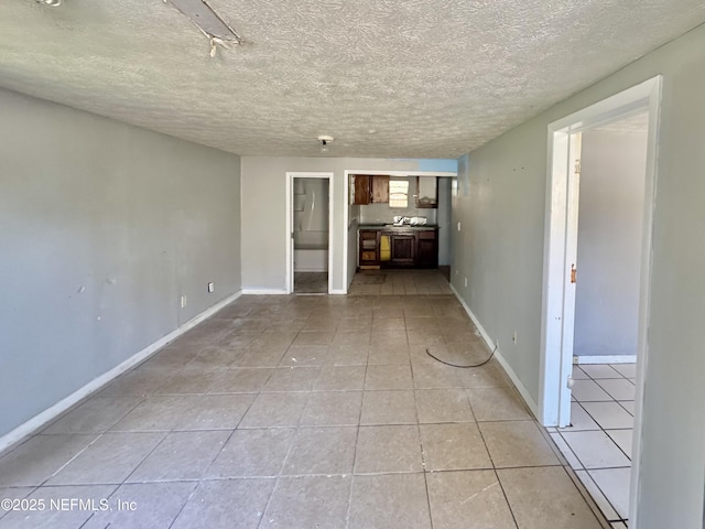 unfurnished living room with light tile patterned floors, baseboards, and a textured ceiling