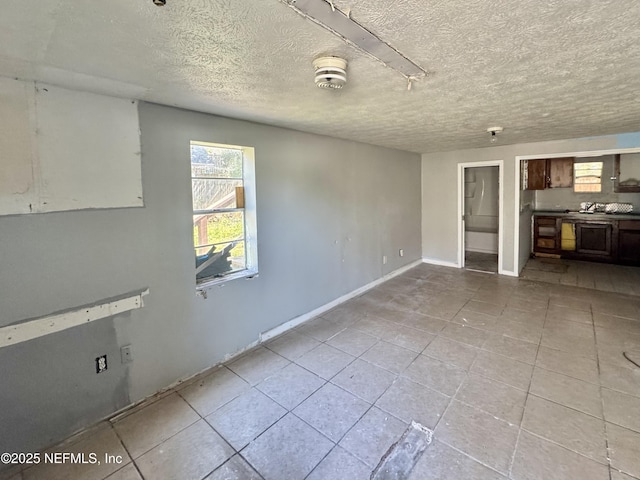 interior space with a textured ceiling, baseboards, and tile patterned floors