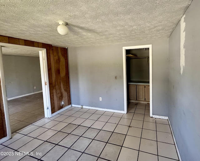 spare room featuring baseboards, a textured ceiling, and light tile patterned flooring