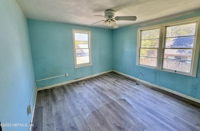 unfurnished room featuring a textured ceiling, ceiling fan, wood finished floors, and baseboards