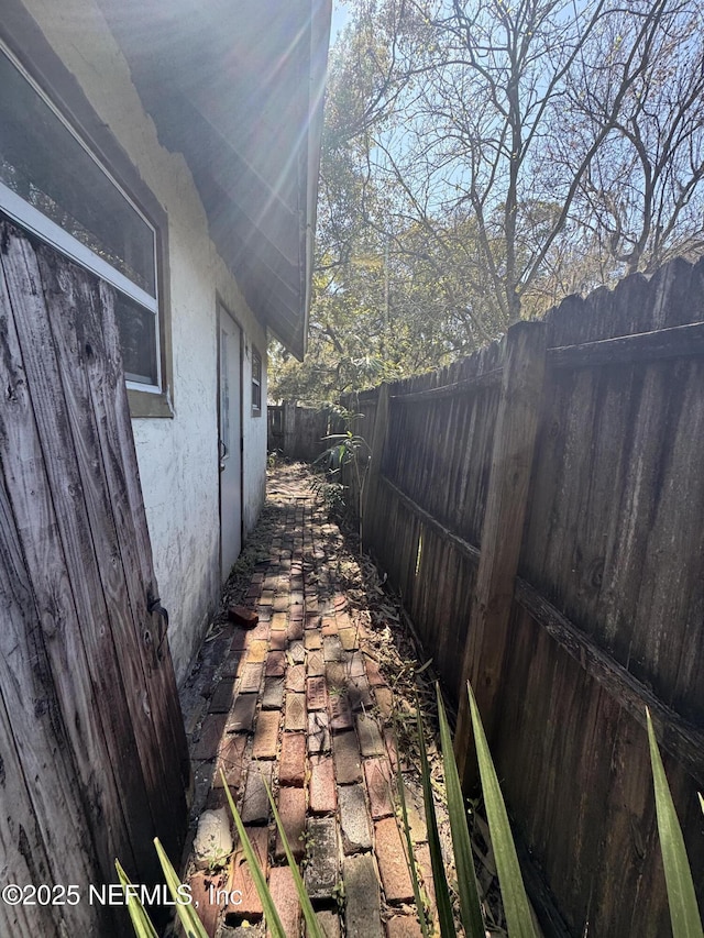 view of side of property with a fenced backyard and stucco siding