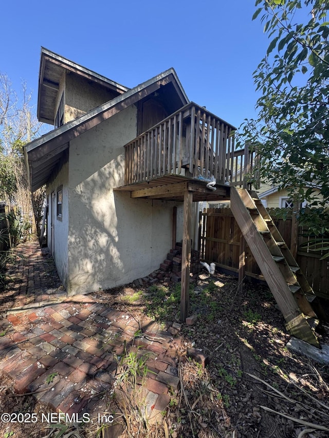 view of side of home featuring a patio area, fence, and stairs