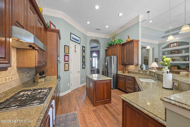 kitchen with arched walkways, extractor fan, a sink, appliances with stainless steel finishes, and light stone countertops