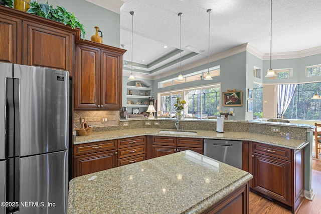 kitchen with a peninsula, stainless steel appliances, crown molding, a textured ceiling, and a sink