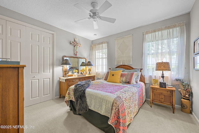 bedroom with light carpet, a textured ceiling, baseboards, and a closet