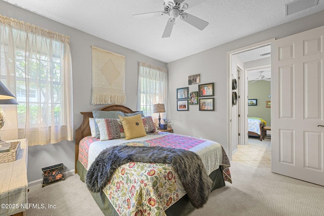 carpeted bedroom with a textured ceiling, baseboards, visible vents, and a ceiling fan