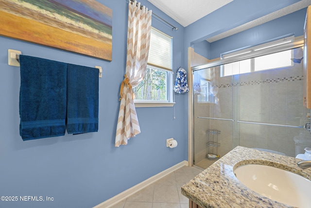 bathroom with tiled shower, tile patterned flooring, vanity, and baseboards