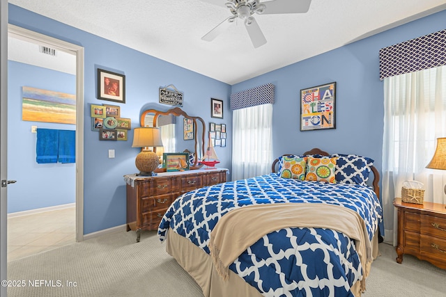 carpeted bedroom featuring a ceiling fan, visible vents, and baseboards