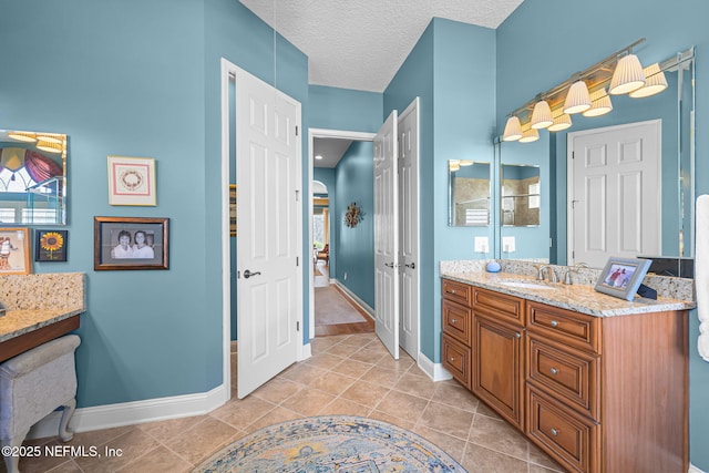 full bath featuring a textured ceiling, tile patterned flooring, vanity, and baseboards