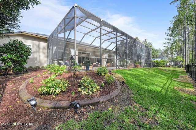 back of house featuring glass enclosure, a fenced backyard, a yard, and stucco siding