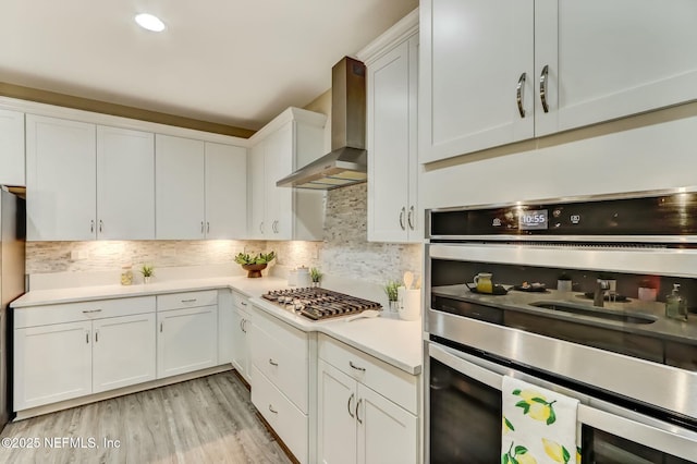 454 Pine Bluff Dr, Saint Augustine, FL 32092 - kitchen featuring decorative backsplash, wall chimney exhaust hood, stainless steel appliances, light countertops, and white cabinetry