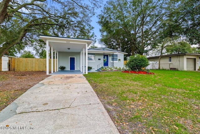 view of front facade with board and batten siding, fence, a front lawn, and concrete driveway