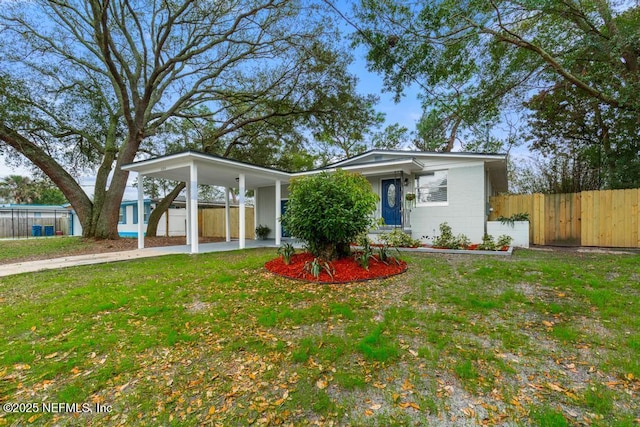 view of front of home featuring concrete block siding, a carport, a front yard, and fence