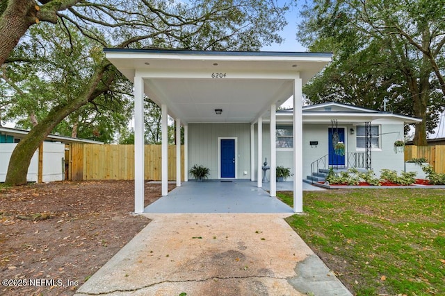 exterior space with a carport, fence, a front lawn, and board and batten siding