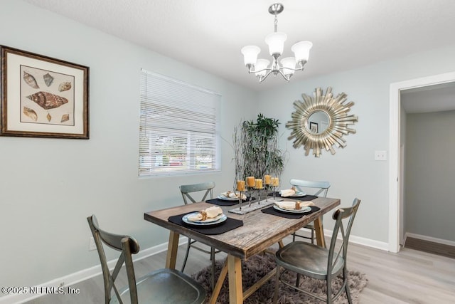 dining area with baseboards, a chandelier, and wood finished floors