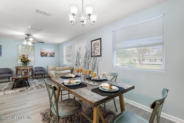 dining room with ceiling fan with notable chandelier, visible vents, baseboards, and wood finished floors